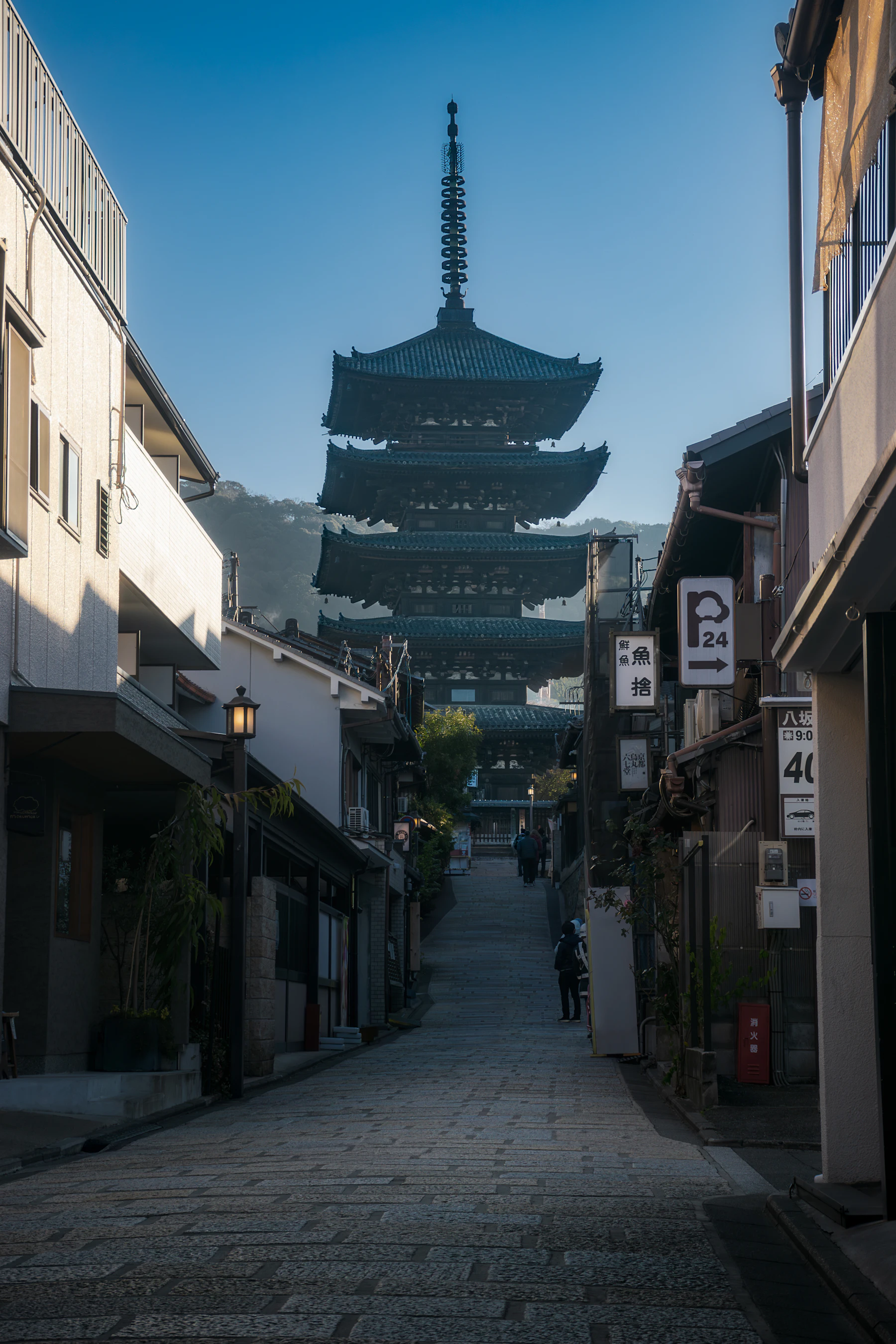 Eine schmale Straße in Kyoto führt im weichen Morgenlicht auf eine Pagode zu