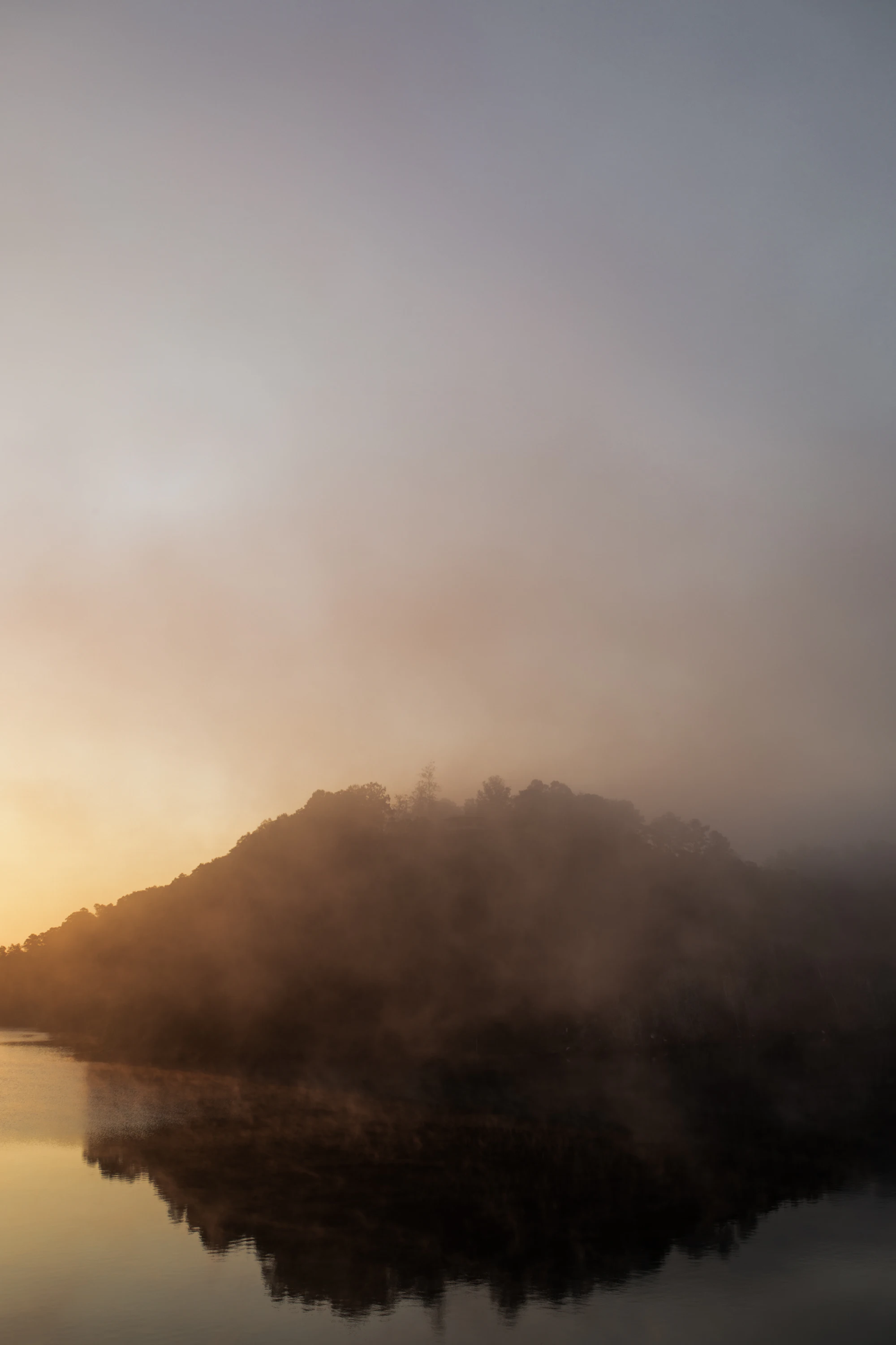 Ein stiller Bergsee liegt unter einer geschlossenen Decke aus Nebel