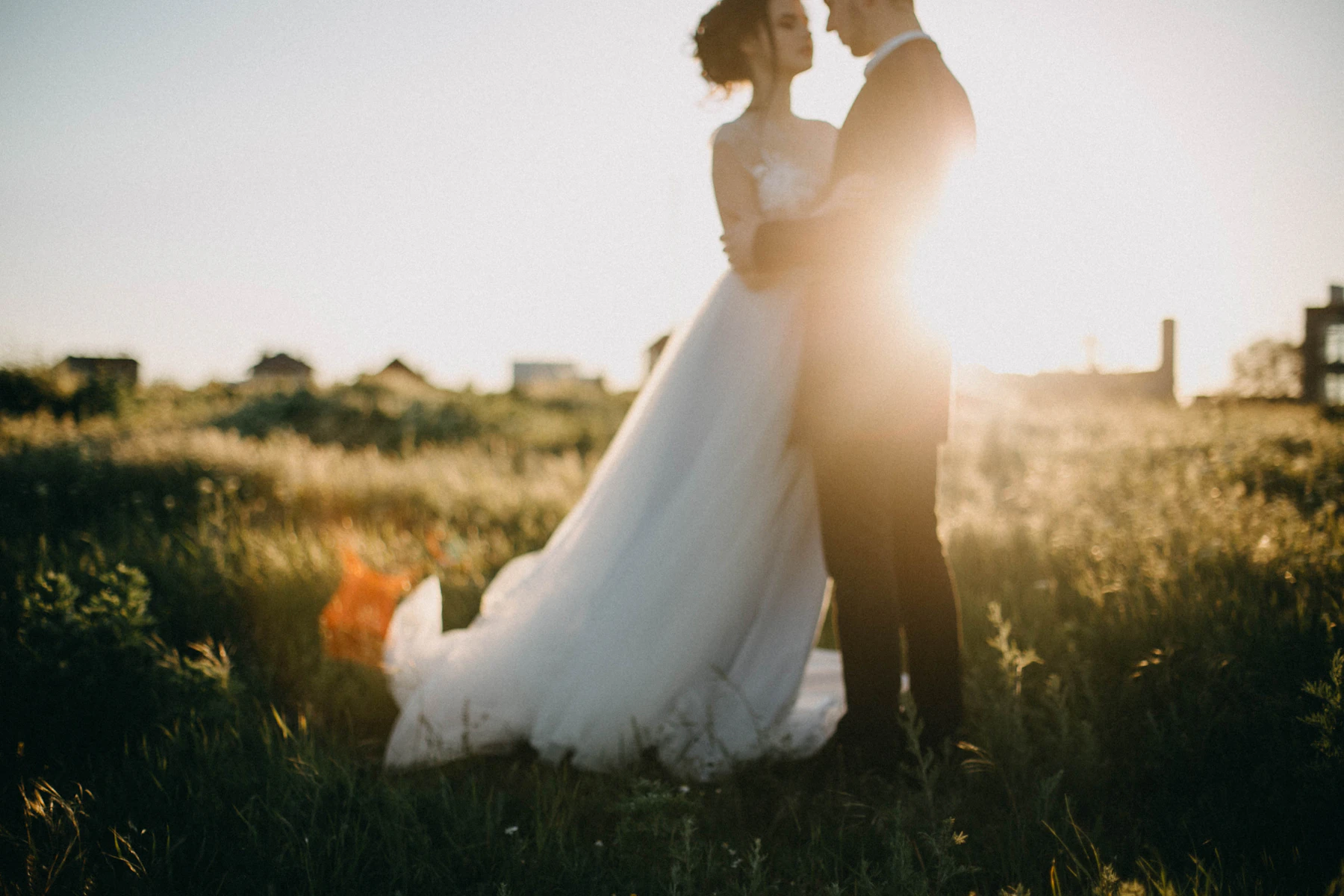 Ein Hochzeitspaar steht sich auf einer Wiese im warmen Abendlicht gegenüber